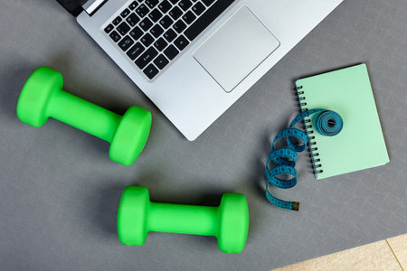 Fitness background with laptop, dumbbells, notebook and measuring tape. Fitness planning concept.の写真素材
