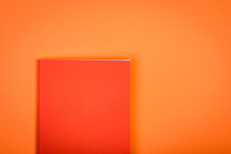 Orange notebook on orange background.の写真素材