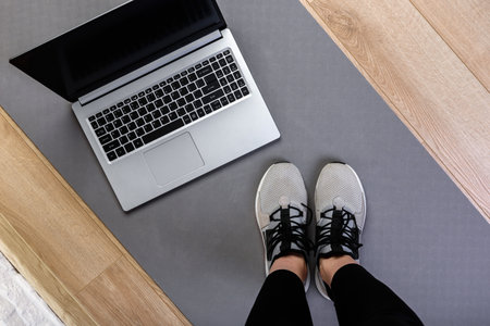 Sporty woman is preparing for workout and is using a laptop at home in the living room.の写真素材