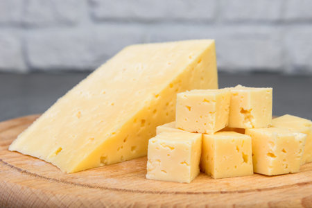 Sliced cheese on wooden board on gray background.の写真素材
