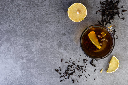 Glass cup of black tea with lemon on gray background.の写真素材