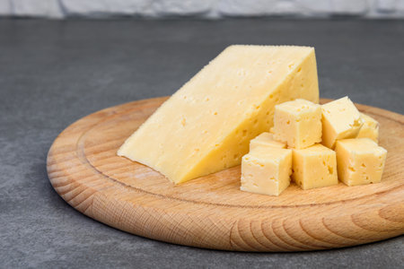 Sliced cheese on wooden board on gray background.の写真素材