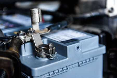 A man installing a new car battery under the hood of a car. Vehicle maintenance and repair.の写真素材