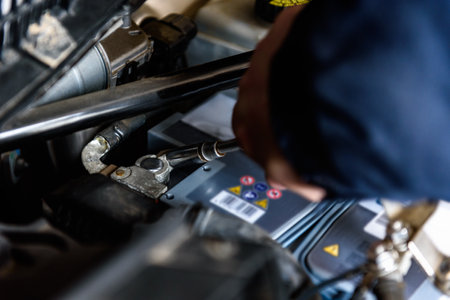 A man installing a new car battery under the hood of a car. Vehicle maintenance and repair.の写真素材