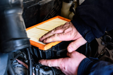 Car mechanic replacing old paper air filter of car and installing new air filter.の写真素材
