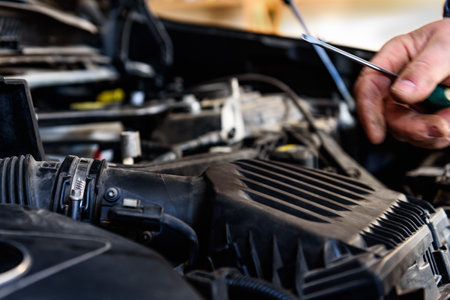 Car mechanic replacing old paper air filter of car and installing new air filter.