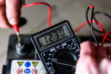 Mechanic holding voltmeter to check voltage car battery. Car repair.の写真素材