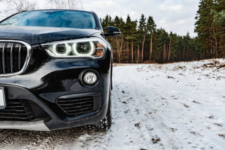 Dirty black car is parked on nature covered by snow in winter.の写真素材