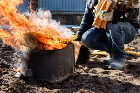 A man burning old unwanted things from home in a bonfire in early spring.の写真素材