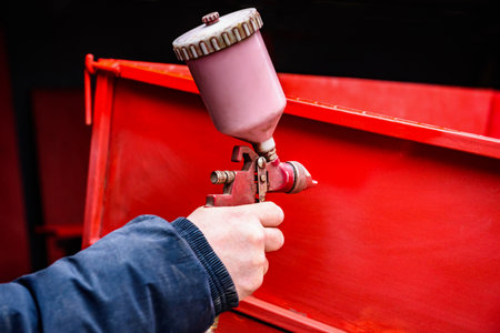 Rebuilding upgrading and modifying trailer. Man painting a metal trailer with spray gun.の写真素材