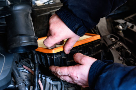 Car mechanic replacing old paper air filter of car and installing new air filter.の写真素材