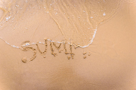 Inscription on wet sand Summer. Concept photo of the beginning and end of the summer holidays.の写真素材