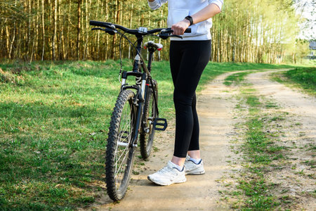 Female cyclist holding the handlebars of a mountain bike is going to ride outdoors against the...