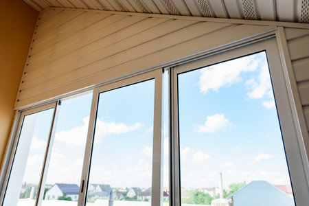 Hand opening white plastic sliding window on balcony.