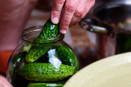 Preservation of seasonal vegetables. Woman putting washed cucumbers in a glass jarの写真素材