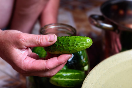 Preservation of seasonal vegetables. Woman putting washed cucumbers in a glass jarの写真素材