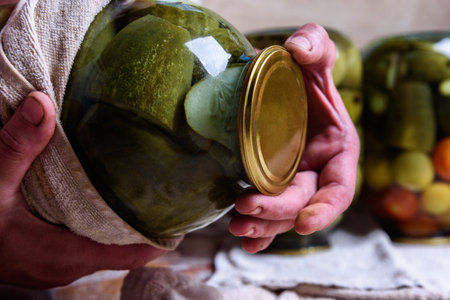 Preservation of seasonal vegetables. A woman checking canned jars of cucumbers and tomatoesの写真素材