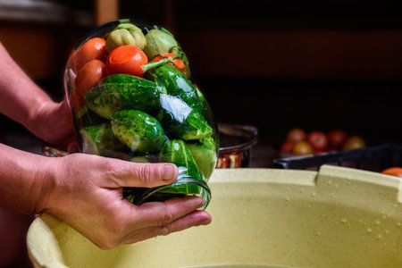 Preservation of season vegetables. Woman putting washed cucumbers in a glass jar.の写真素材