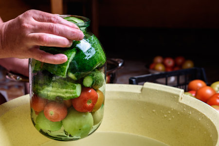 Preservation of season vegetables. Woman putting washed cucumbers in a glass jar.の写真素材