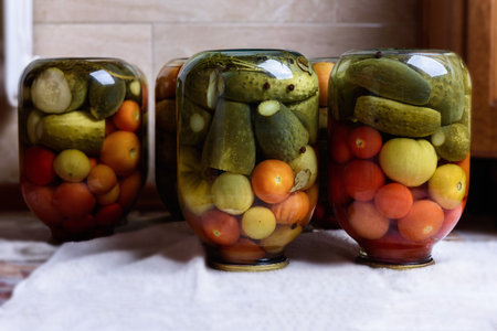Preservation of season vegetables. Canned jars of cucumbers and tomatoes. Ð¡ooking marinated...