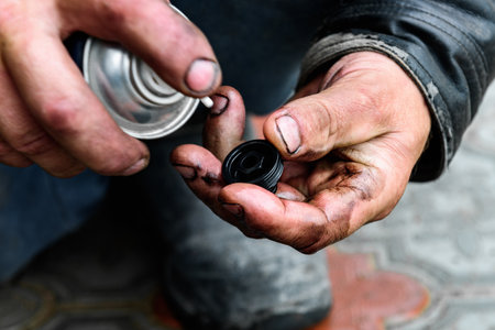 A car mechanic cleaning the body part of an old oil filter using a special cleaner