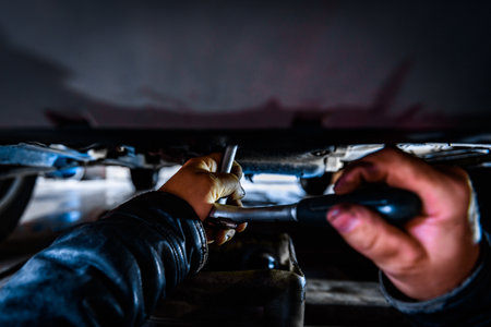 A car mechanic installing and screwing a new oil filter under the car using a wrenchの写真素材