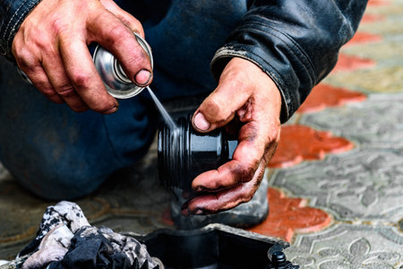 A car mechanic cleaning the body part of an old oil filter using a special cleanerの写真素材
