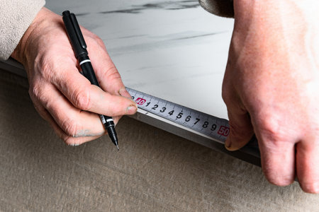 Measuring tiles with a tape measure before cutting
