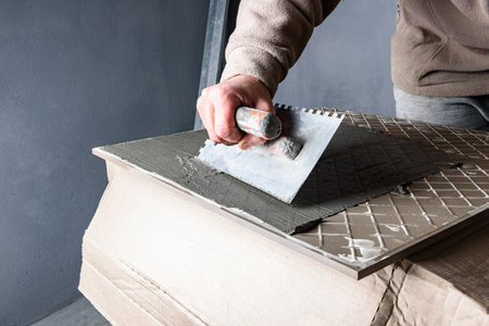 Applying glue on ceramic tile with a spatula