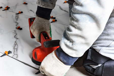 Tiler laying tiles on wall using electric vibrating suction cupの写真素材