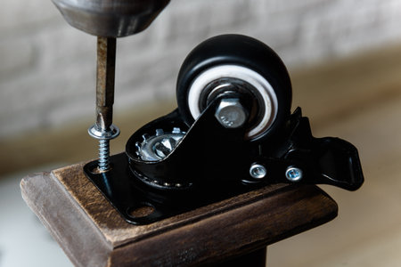 Screwing furniture wheels with brakes to a table with a screwdriver
