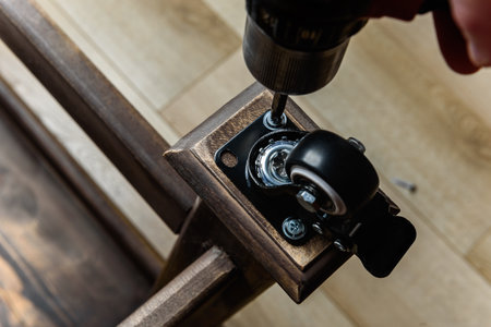 Screwing furniture wheels with brakes to a table with a screwdriver