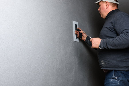 Worker using a float to smooth decorative pebble plaster on a wall.の写真素材