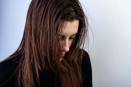Young woman with dirty greasy hair on gray background