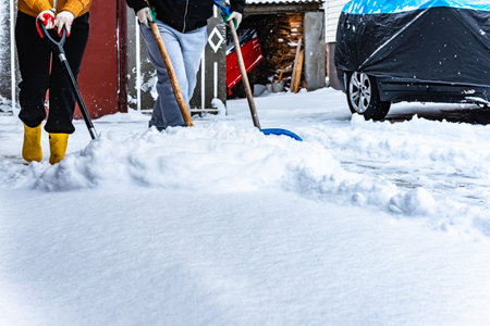People shoveling snow in their yard using three plastic snow shovel after snowfall.の写真素材
