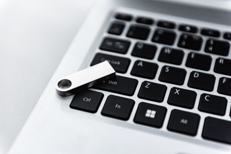 Silver USB flash drive on laptop keyboard
