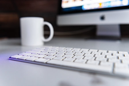 Office workplace with silver black monoblock pc and white keyboard and mouse on white table
