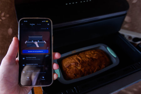 A woman's hand controls an aerogrill from a mobile phone