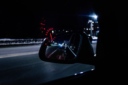 Overtaking car in the rear view mirror in evening night time