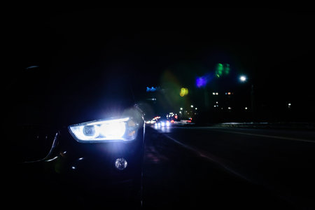 Car with bright headlights parked on city street in evening night time