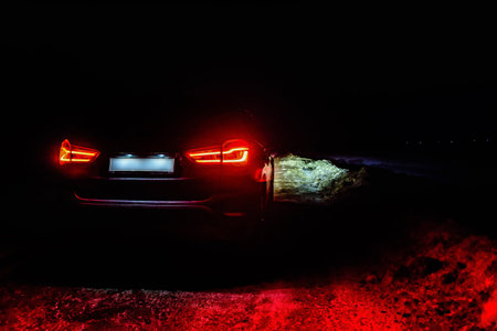 Car with bright headlights parked on city street in evening night time