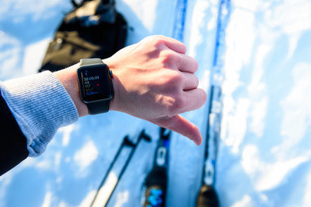 Skier checking fitness tracker while cross-country skiing in a snowy forest