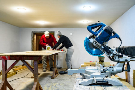 Carpenter using circular saw for cutting wooden OSB board