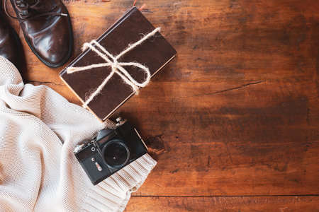 Men's brown boots, sweater, book and camera in retro style. Free space for text.の写真素材