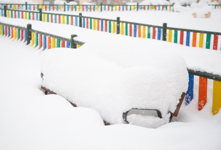 A bench covered with snow on the background of a colored fence. Snowfall in Spain, January 2021.の写真素材
