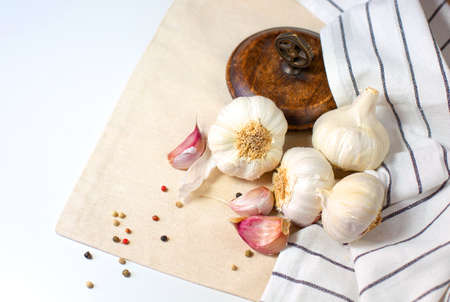 Several heads of garlic and cloves of garlic lie on a tea towel against a light background. Free space for text.の写真素材