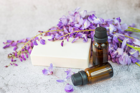 White soap, two jars of natural oil and fresh flowers are on a gray background. Natural cosmetics theme.の写真素材