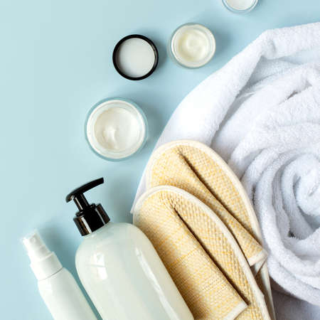 Spa and beauty. Set of cosmetic products and spa supplies. White towel, creams and bath slippers are on a light blue background.の写真素材