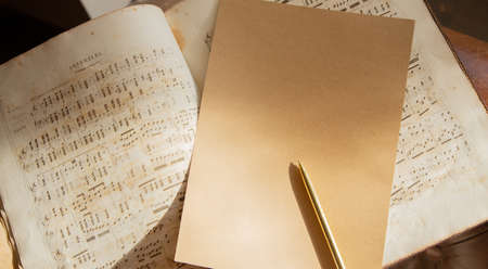 Opened music old book with a sheet of paper and a gold pen. Free space for text. Retro style.