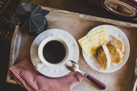 A breakfast tray with a fried toast, a cup of black coffee and a coffee pot is on a table near with radio. Retro style.の写真素材